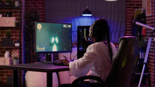 Woman playing multiplayer space shooter simulation enjoying free time using pc gaming setup