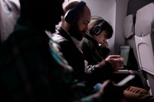 Diverse people travelling on airplane and using laptop