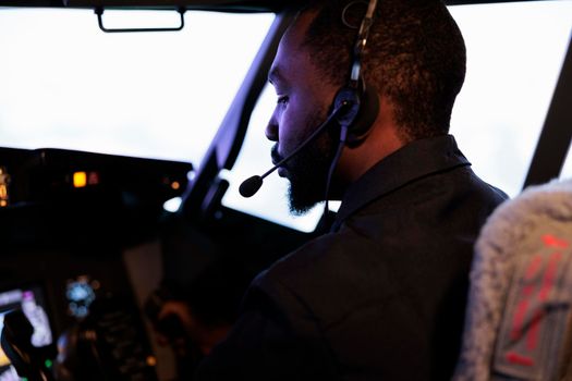 African american copilot flying airplane in cockpit with captain