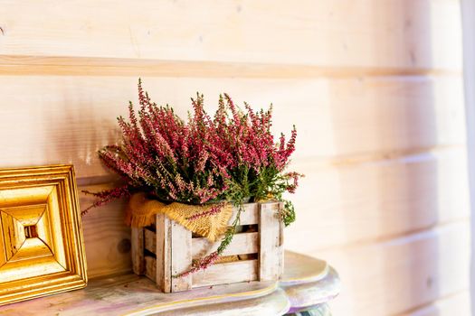 home balcony decor with pink heather flowers in wooden box, candlelight flame, autumn hygge home decor.Still life details of cozy interior in rustic style. Scandinavian style.decoration element