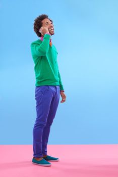 Talking about style...Studio shot of stylish young man talking on the phone against a colorful background.