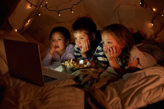 Our pillow for is the bomb. three young children using a laptop in a blanket fort.