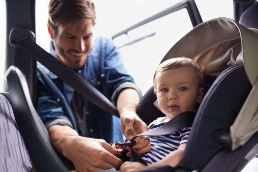 Safety first when your most precious gift is on board. A young father strapping his baby into a car seat.