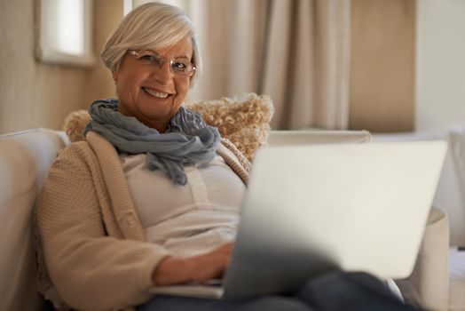 Enjoying a bit of web browsing. A happy senior woman working on her laptop at home.
