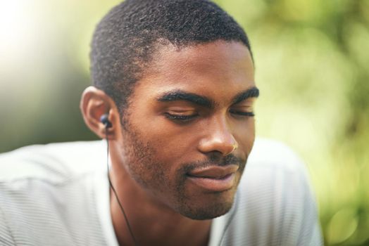 Feeling the beat. a young man listening to music outdoors.