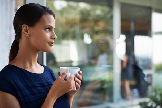 Take a moment for quiet contemplation. an attractive young woman enjoying a freshly brewed cup of coffee.