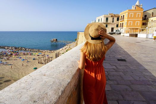 Back view of young woman walking in the historic town of Termoli, Molise, Italy