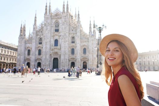 Tourism in Italy. Beautiful smiling girl sitting with Milan Cathedral on the background in Italy.
