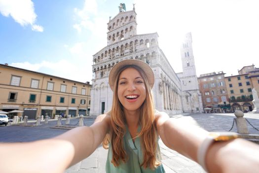 Smiling traveler girl takes selfie photo in the historic town of Lucca, Tuscany, Italy