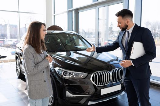a salesman in a car dealership talks about the benefits of a new SUV to a buyer