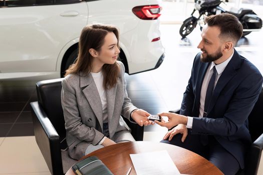 car dealership manager handing over keys to new car buyer. the concept of buying a car on lease