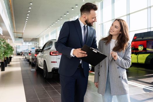 an employee of a car dealership helps to sort out a car insurance buyer woman