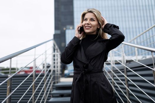 portrait of a confident middle-aged business woman talking on a mobile phone against the backdrop of an office skyscraper