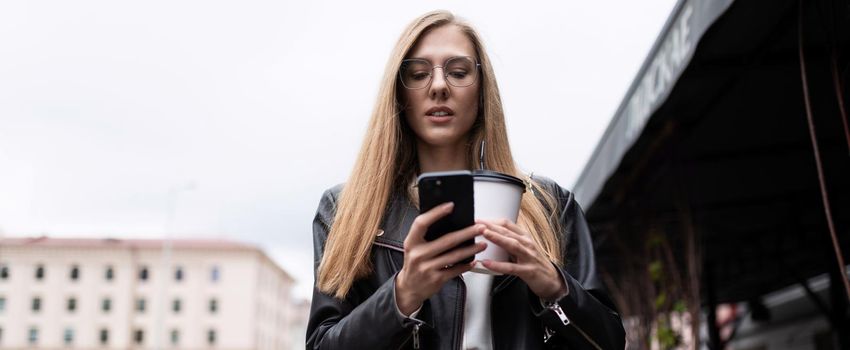 portrait of a serious young woman with a cup of coffee looking at a mobile phone