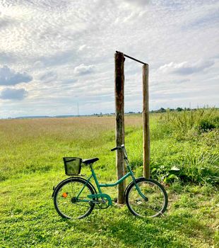 Bike stands on the background of beautiful nature - field sky grass clouds. Ecotourism, recreation, naturalism.