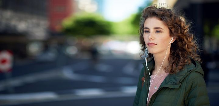 beautiful woman walking in city street listening to music wearing earphones urban lifestyle