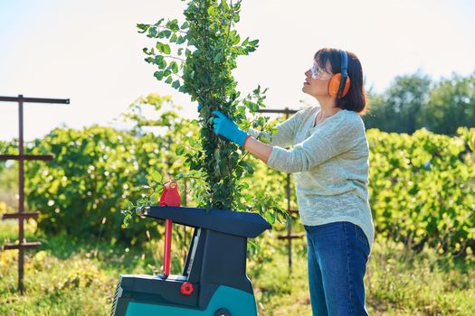 Woman using electric garden shredder for branches and bushes