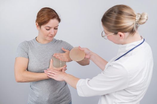 Caucasian woman trying on breast implants. A plastic surgeon helps a patient with a choice.