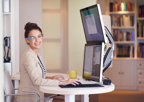 My glasses make business portable. Portrait of a young woman wearing smart glasses while working on a dual-screen computer.
