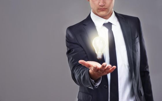 Lighting the way to sustainable business practices. A businessman holding a glowing light bulb.