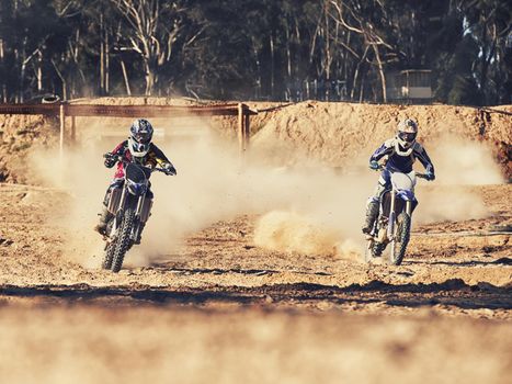 Time to rip up this track. two motocross racers speeding along the track.