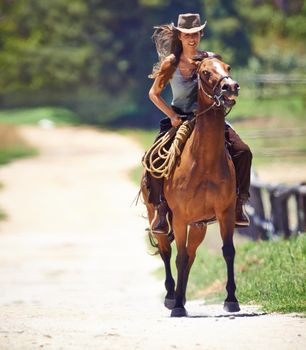 Loving the outdoors. Action shot of a beautiful young cowgirl riding her horse.
