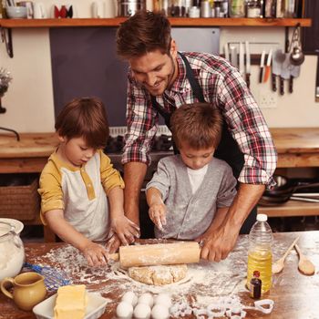 You boys are doing so well. Two cute little boys baking with their father in the kitchen.