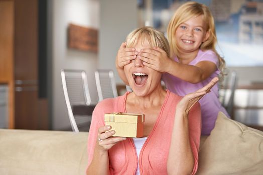 Open your hands and close your eyes for a big surprise. a young girl surprising her mother with a gift.