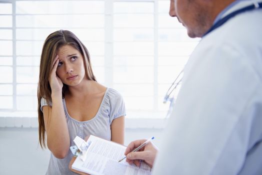 So, how long have you been having these headaches. A young woman looking concerned during a visit to the doctor.