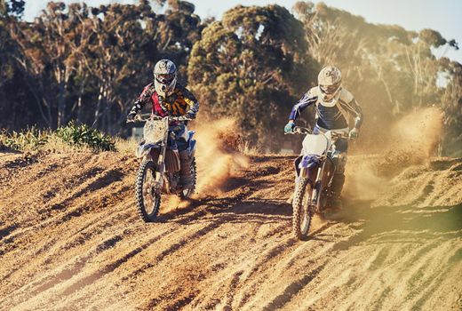 Time to rip up this track. a two motocross riders racing with a trial of dust behind them.