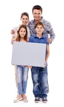 Every family needs this...Portrait of a family of four holding up a blank placard for copyspace, isolated on white.