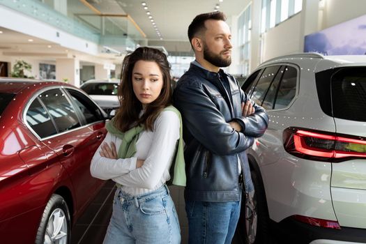 frustrated man and woman at car dealership can't agree on buying a new car