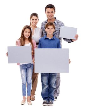 Theres something for all of us. Portrait of a family of four holding up a blank placard for copyspace, isolated on white.