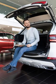 A man sits in the trunk of an SUV and dreams of buying it