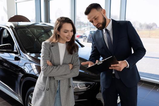 an employee of a car shop draws up documents for a new car for a woman buyer