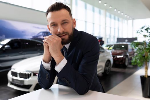portrait of a businessman in the car showroom of a car dealership