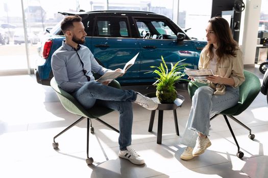a young married couple picks up insurance for a car in a car dealership