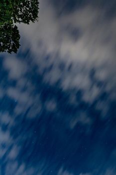 Dark blue sky on long exposure with moving clouds at night 