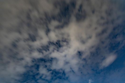 Dark blue sky on long exposure with moving clouds at night 