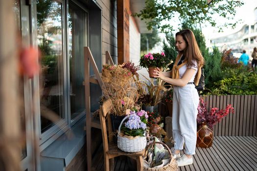 European woman chooses flowers as a gift in a street garden stall