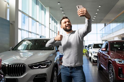 the buyer takes a selfie after buying a new car against the backdrop of the showroom