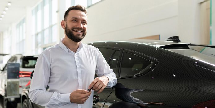young businessman purchases a new car in a car dealership