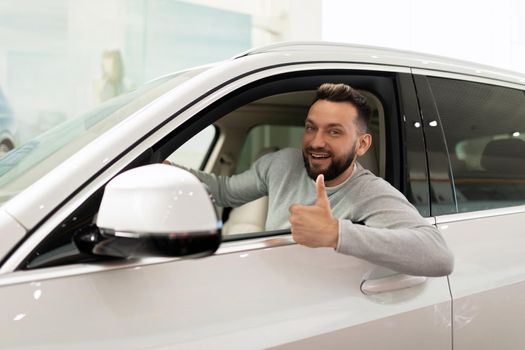 satisfied man in a new SUV bought at a car dealership with a smile on his face