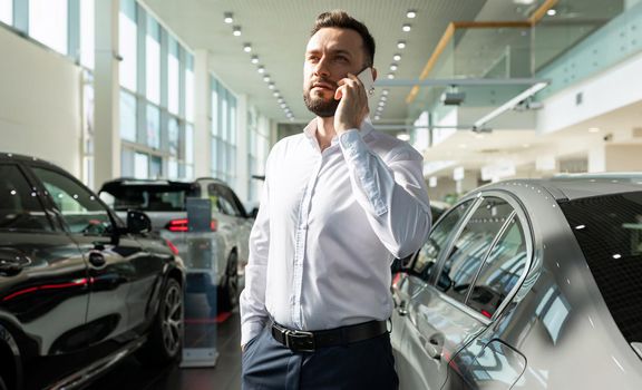 businessman chooses a new car in a premium car dealership