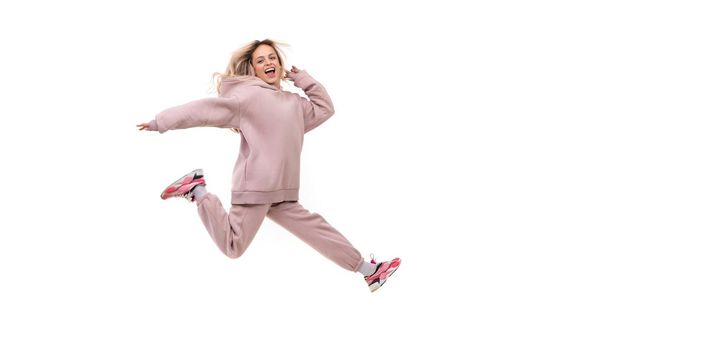 young woman in a jump in a tracksuit of beige color on a white isolated background