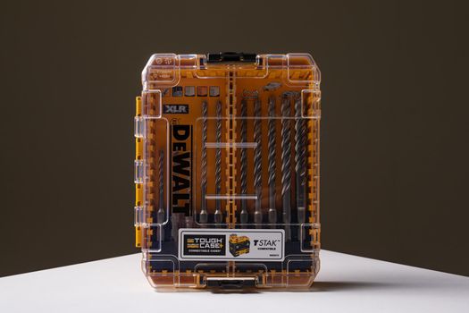 Photo shot of orange and transparent kit box with drills for drilling holes on a white table and isolated on background. Repair and construction concept. Dewalt