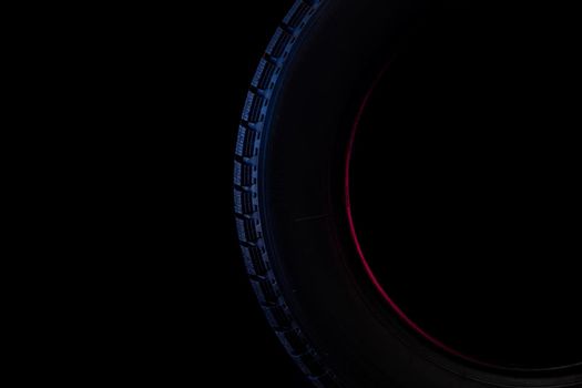 image photograph of a part of a tire with a winter tread on a black background