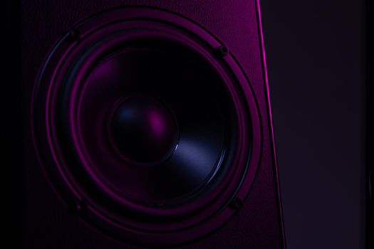 large speaker close-up on a black background with violet-purple illumination close-up, music playback on a luxury speaker system