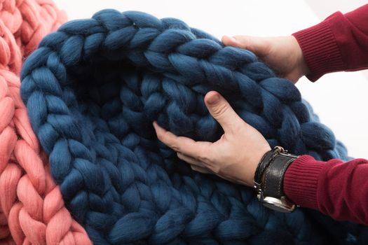 men's hands touching a coarse-knit blanket made of natural wool