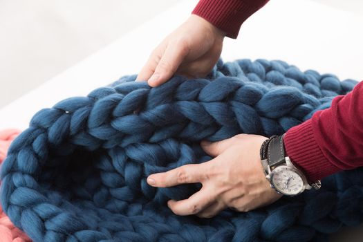 a coarse knit blanket made of natural wool in the hands of a man